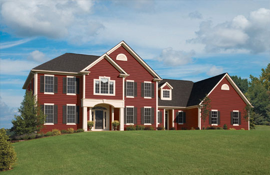 Red vinyl siding home with white trim and a landscaped front lawn.